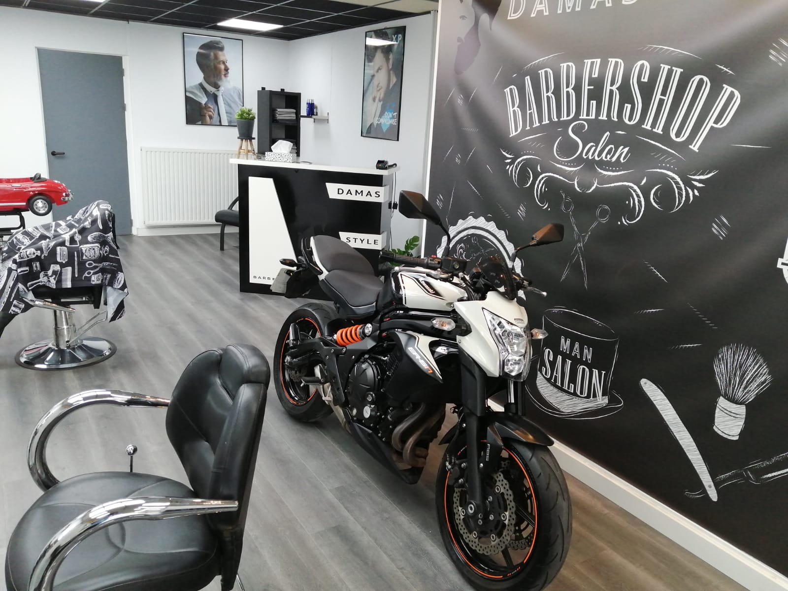 De salon van Damas Style met de krijtbanner en een motor binnen