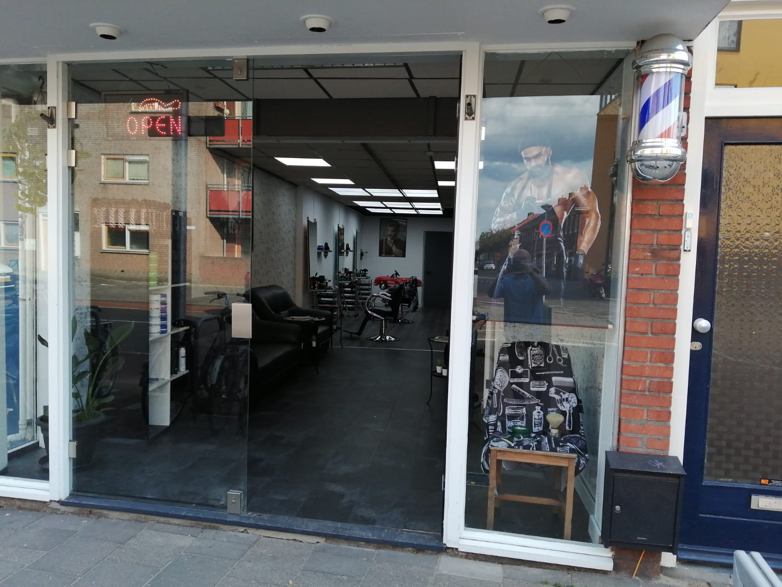 De ingang van Damas Style met de barberspaal en het OPEN-bord